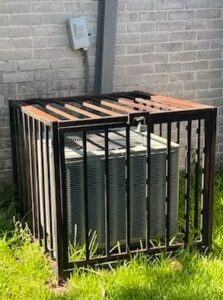 AC enclosed in a wrought iron cage to protect it from theft and vandalism